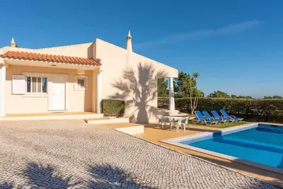 a villa with a swimming pool in front of a house at Villa Costa in Albufeira