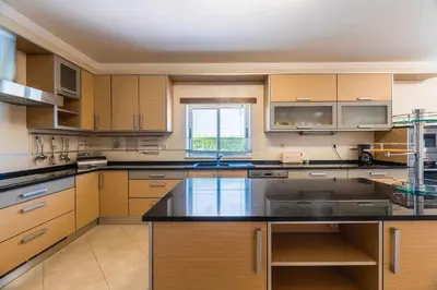 a kitchen with wooden cabinets and a black counter top at Villa Hunês in Guia