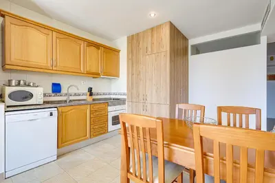 a kitchen with wooden cabinets and a wooden table and chairs at Apartment with 2 bedrooms at Vilamoura Marina in Quarteira