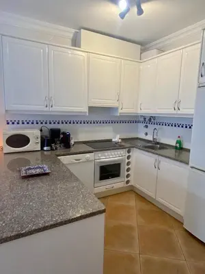 a white kitchen with white cabinets and a sink at Sunbliss - praia, piscina e localização central in Albufeira