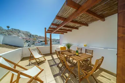 a patio with a wooden table and chairs on a balcony at Casa Estrela do Mar in Albufeira