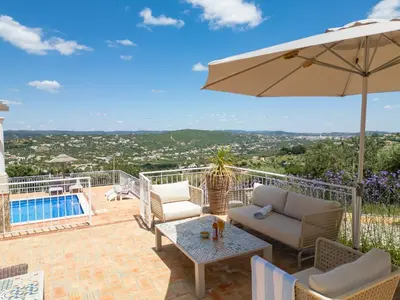 a patio with a table and an umbrella and a pool at Casa Quadra Dique in Faro