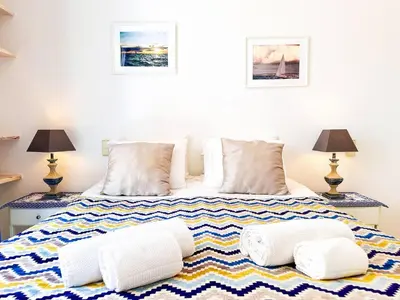 a bedroom with a bed with pillows and two lamps at Ocean Breeze WindMill Condo by BeCherish in Albufeira