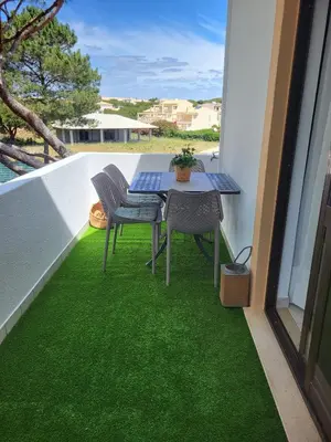 a table and chairs on a balcony with green grass at T2 Falésia - Olhos de Água in Olhos de Água