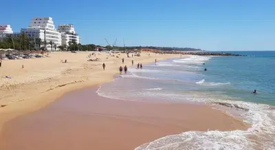 a beach with a lot of people in the water at Nice Flat in Quarteira Beach in Quarteira