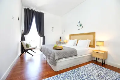 a bedroom with a bed and a chair and a window at Nap in the shade Apartment in Faro