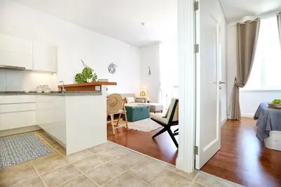 a kitchen with white cabinets and a living room at Maison Faro Luxe - A Tranquil Retreat by the Algarve Coast in Faro