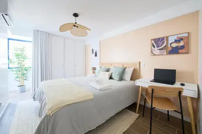 a bedroom with a bed and a desk with a laptop on it at Amazing Flat, 100m from beach in Quarteira