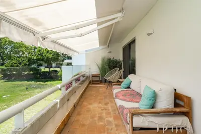 a patio with a couch and an umbrella at BmyGuest Collection - Quinta do Lago Luxury Beach Apartment in Almancil