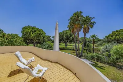two white chairs sitting on a yellow roof with a monument at Villa Casa Jasmim by Villa Plus in Quarteira