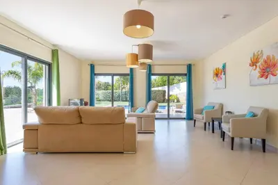 a living room with a couch and chairs and windows at Villa Monte Avós by Ecovillas Albufeira in Albufeira