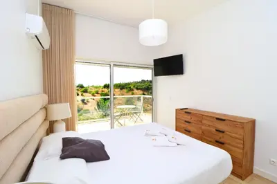 a bedroom with a white bed and a large window at Serenity 18 House by Stay ici Algarve Holiday Rental in Albufeira