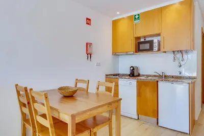 a kitchen with a wooden table and a small kitchen with a table and chairs at Side Villas - 1bdr Retreat with BBQ & Patio in Quarteira