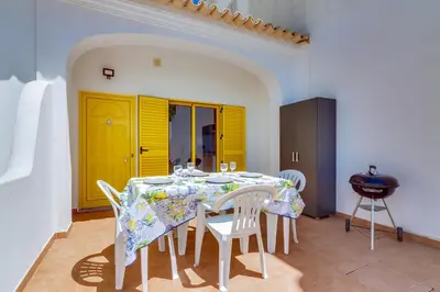 a dining room with a table and white chairs at Side Villas - 1bdr Retreat with BBQ & Patio in Quarteira