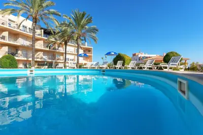 a group of chairs and umbrellas on a patio at BnB Homes Apartment with cozy Terrace & 2 Swimming pools near the heart city in Albufeira