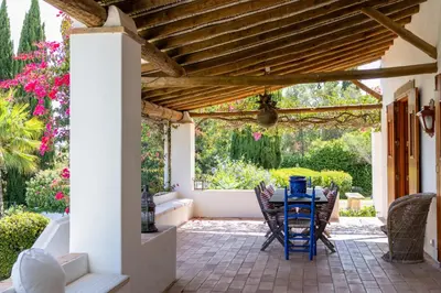 a patio with a table and chairs under a wooden pergola at Almancil Sea and Countryside Secluded Villa in Quartos