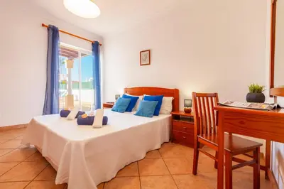 a bedroom with a bed with blue pillows and a desk at Villa Azzurra by Algarve Vacation in Albufeira