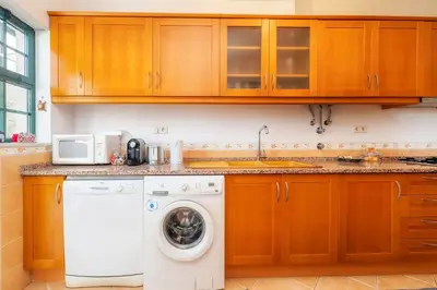 a kitchen with a washing machine and a microwave at Calm Paradise close to the City in Faro