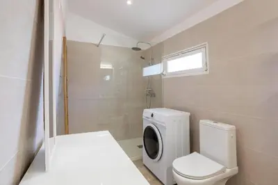 a bathroom with a toilet and a washing machine at Villa Mar e Sol by HelloVacations in Olhos de Água