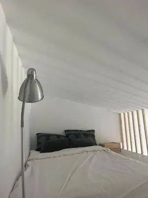 a white bedroom with a bed and a lamp at Casa das Mélias in Vilamoura