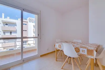 a dining room with a table and a large window at Apartamento Al Sakia 2bdr com piscina e ar condicionado in Quarteira