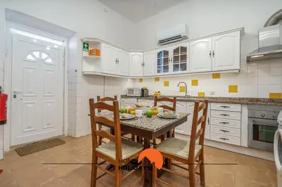 a kitchen with white cabinets and a table and chairs at #236 Texugueiras 148 by Home Holidays in Ferreiras