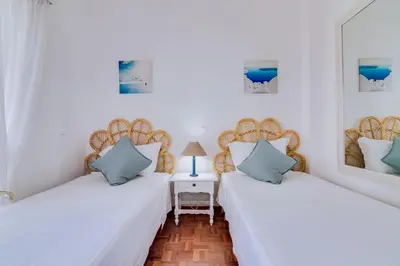 two beds in a room with white walls and blue pillows at Maresia 2 Bedroom Oceanfront Apartment in Quarteira in Quarteira