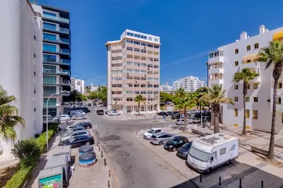 a city street with cars parked in a parking lot at Maresia 2 Bedroom Oceanfront Apartment in Quarteira in Quarteira