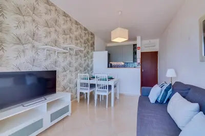 a living room with a couch and a tv and a table at Maresia 2 Bedroom Oceanfront Apartment in Quarteira in Quarteira