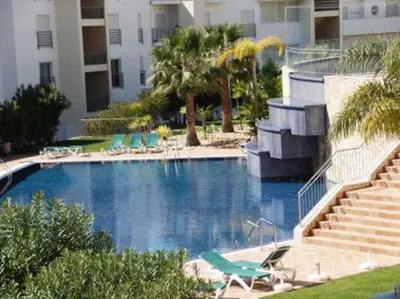a large swimming pool with chairs and a building at Encosta Do Sol in Albufeira