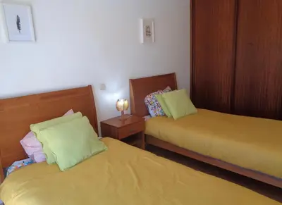 a room with two beds with green and pink pillows at Apartamento Citimar in Vilamoura