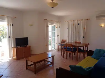 a living room with a television and a table and chairs at Apartamento Citimar in Vilamoura