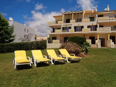 a group of yellow chairs in front of a building at Apartamento Citimar in Vilamoura