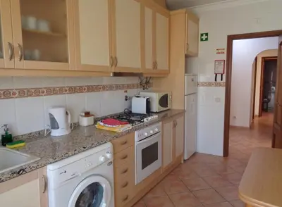 a kitchen with a washing machine and a microwave at Apartamento Citimar in Vilamoura