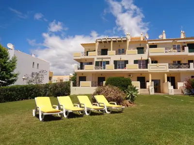 a group of yellow chairs in front of a building at Apartamento Citimar in Vilamoura
