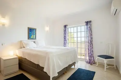 a white bedroom with a bed and a window at Villa Nascente Balaia in Branqueira