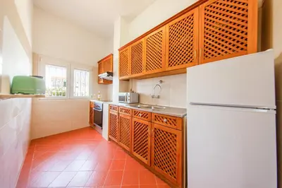 a kitchen with a white refrigerator and a red tile floor at Villa Palancar by Algarve Vacation in Albufeira
