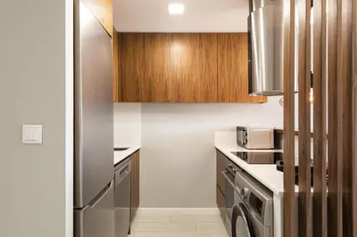 a kitchen with a stainless steel refrigerator and wooden cabinets at SeaVillage Asia - City Center by HD in Vilamoura