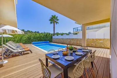 a patio with a table and chairs and a swimming pool at Villa Casa Joao by Villa Plus in Albufeira