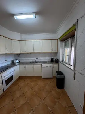 a kitchen with white cabinets and a tile floor at Casa Vila Sul AE in Roja- Pé