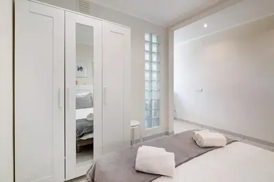 a white bedroom with a bed and two slippers at Bay View Albufeira in Albufeira
