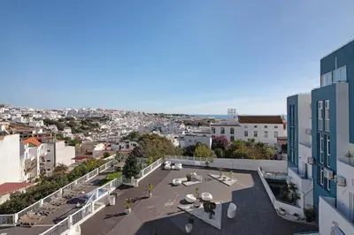 a white living room with a table and a television at Bay View Albufeira in Albufeira