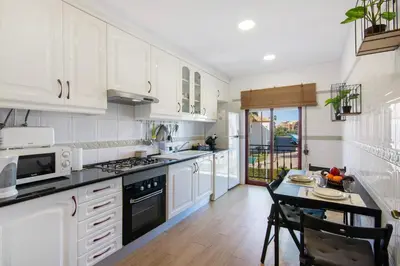 a kitchen with white cabinets and a table in it at Cosy Apartment With Pool 2 in Vilamoura