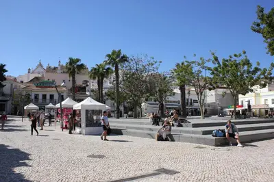 a group of people sitting on steps in a plaza at Paulos Studio in Faro