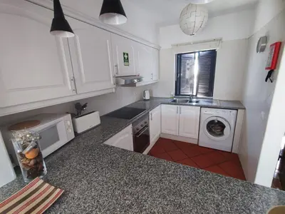 a kitchen with white cabinets and a washing machine at Albufeira, T1 in Balaia Golf Village, Algarve in Albufeira