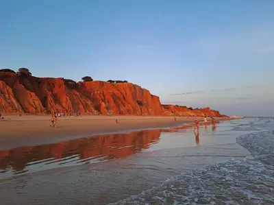 a group of people walking on a beach next to a cliff at Praia da Falésia, O Melhor Estúdio da Aldeia das Acoteias in Albufeira