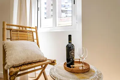 a bottle of wine sitting on a table next to a chair at Casas das Ilhas in Faro