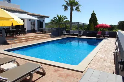 a swimming pool in a yard with chairs and umbrellas at Holiday home in Santa Barbara de Nexe - Algarve 51807 in Santa Bárbara de Nexe