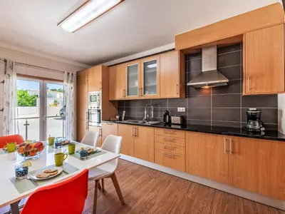 a kitchen with wooden cabinets and a white table and chairs at Holiday Home Vila Parra by Interhome in Galé