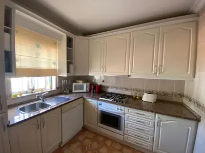 a kitchen with white cabinets and a sink and a stove at Vila Rafaella - Praia de São Rafael in Sesmarias